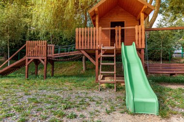 Yazın parktaki yeşil bahçeye kurulmuş boş, modern ahşap çocuk oyun parkı. Çocuklar için komik bir yer. Çocuklar için şehir içi spor aktiviteleri. Mahallenin çocukluk kavramı
