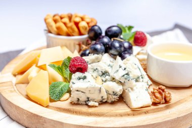 Farklı peynir çeşitleri olan bir pano. Peynirler, peynirli, peynirli, peynirli, peynirli, peynirli, ballı, peynirli, peynirli, peynirli, peynirli ve üzümlü karışımı. Restoran menüsü kahvaltı tabağı. Sağlıklı çerez çeşitleri