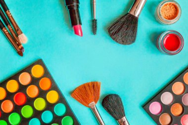Makyaj ve kozmetik için farklı göz falı tonları ve renkli mavi pastel arka planda makyaj fırçası. Üst görünüm düz yatay ve resim gibi