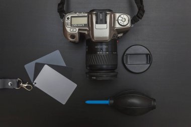 DSR kamera sistemi, kamera temizleme seti, siyah masa arka planında lens ve kamera aksesuarları olan fotoğrafçı işyeri. Hobi seyahat fotoğrafçılık konsepti. Düz görünüm kopyalama alanı
