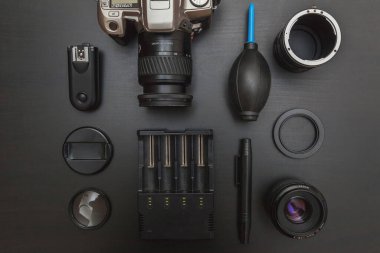 DSR kamera sistemi, kamera temizleme seti, siyah masa arka planında lens ve kamera aksesuarları olan fotoğrafçı işyeri. Hobi seyahat fotoğrafçılık konsepti. Düz görünüm kopyalama alanı