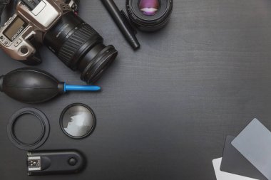 DSR kamera sistemi, kamera temizleme seti, siyah masa arka planında lens ve kamera aksesuarları olan fotoğrafçı işyeri. Hobi seyahat fotoğrafçılık konsepti. Düz görünüm kopyalama alanı