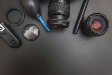 DSR kamera sistemi, kamera temizleme seti, siyah masa arka planında lens ve kamera aksesuarları olan fotoğrafçı işyeri. Hobi seyahat fotoğrafçılık konsepti. Düz görünüm kopyalama alanı