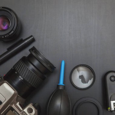 DSR kamera sistemi, kamera temizleme seti, siyah masa arka planında lens ve kamera aksesuarları olan fotoğrafçı işyeri. Hobi seyahat fotoğrafçılık konsepti. Düz görünüm kopyalama alanı