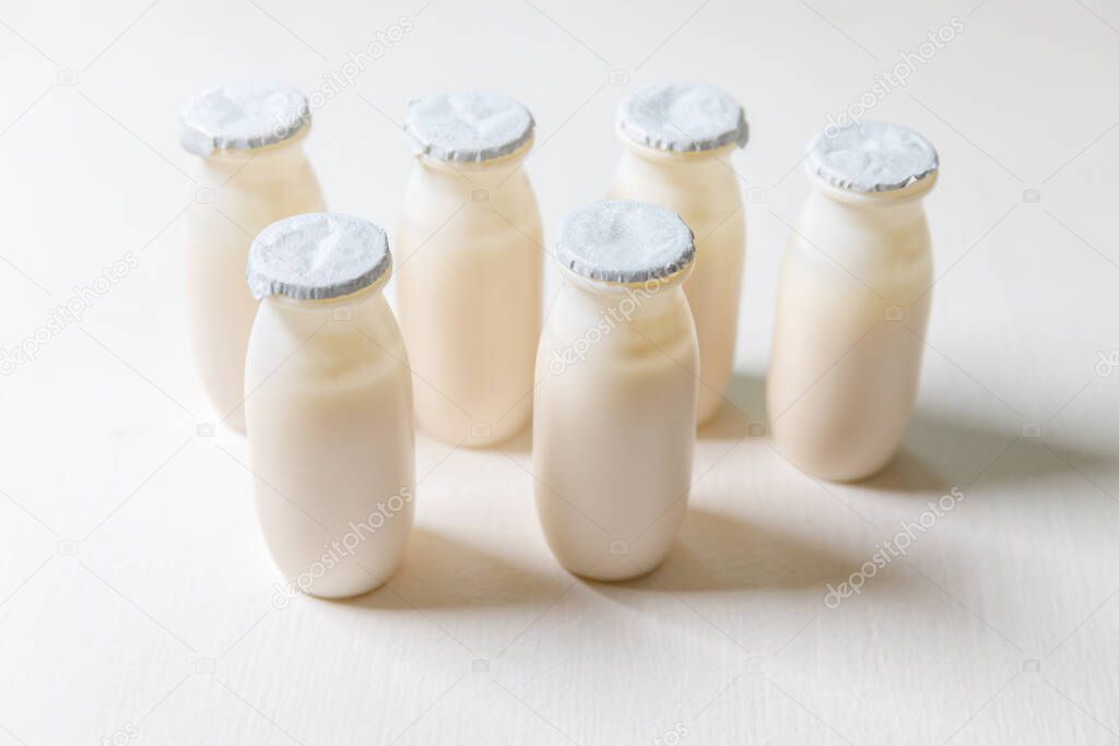 Small bottles with probiotics and prebiotics dairy drink on white background. Production with biologically active additives. Fermentation and diet healthy food. Bio yogurt with useful microorganisms