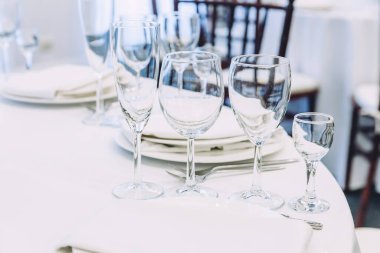 Restoranda peçete bardaklarıyla yemek masası, lüks bir iç mekan. Şık bir düğün ziyafeti dekorasyonu ve yemek servisi tarafından beyaz masa örtüsü üzerinde hazırlanmış yiyecekler.