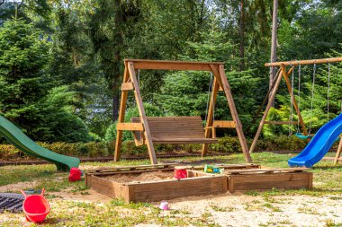 Yazın parktaki yeşil bahçeye kurulmuş boş, modern ahşap çocuk oyun parkı. Çocuklar için komik bir yer. Çocuklar için şehir içi spor aktiviteleri. Mahallenin çocukluk kavramı