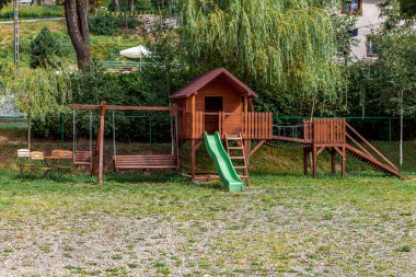 Yazın parktaki yeşil bahçeye kurulmuş boş, modern ahşap çocuk oyun parkı. Çocuklar için komik bir yer. Çocuklar için şehir içi spor aktiviteleri. Mahallenin çocukluk kavramı