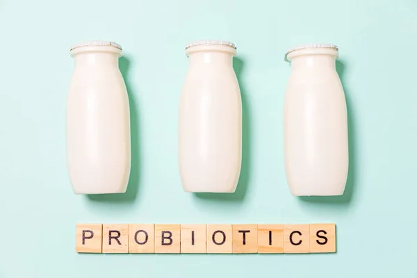 Small bottles with probiotics and prebiotics dairy drink on blue background. Production with biologically active additives. Fermentation and diet healthy food. Bio yogurt with useful microorganisms