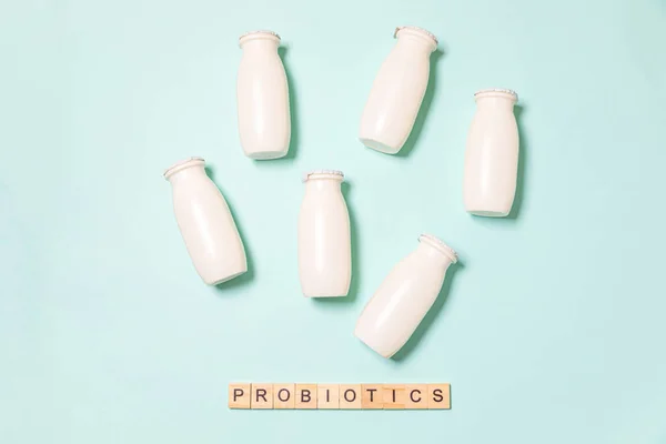 Small bottles with probiotics and prebiotics dairy drink on blue background. Production with biologically active additives. Fermentation and diet healthy food. Bio yogurt with useful microorganisms