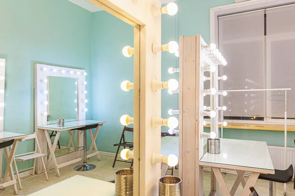 Empty woman makeup place with mirror and bulbs. Workplace makeup artist in modern makeup room. Barbershop interior. Dressing room with makeup mirror and table. Modern classical style interior design
