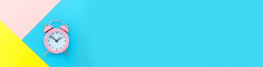 Pankart. Çan çalan klasik alarm saati mavi pembe renkli geometrik arka planda izole edilmiş. Hayatın dinlenme saatleri. İyi sabahlar. Uyanık kalma kavramı. Düz görünüm kopyalama alanı