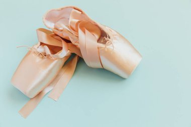 Mavi arka planda saten kurdeleli yeni pastel bej bale ayakkabıları. Dans eğitimi için klasik balerin ayakkabıları. Bale okulu konsepti. Üst görünüm düz kopya alanı