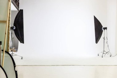 Işık ekipmanlı boş fotoğraf stüdyosu. Profesyonel araç gereçleri ile fotoğrafçı iç mimari. Flaş ışığı, beyaz arka plan çekim için hazır. Modern fotoğraf stüdyosu