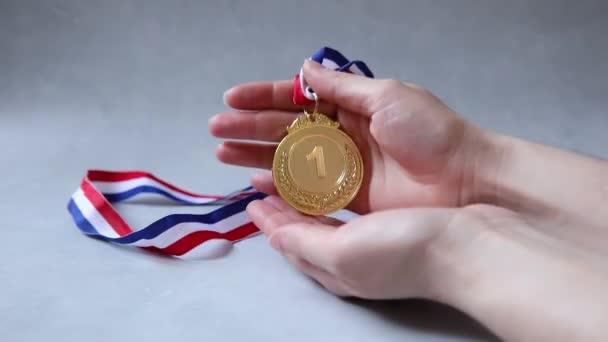 Hand holding winnaar of kampioen gouden trofee medaille op beton steen grijze achtergrond. Overwinning eerste plaats van de concurrentie. Winnings- of succesconcept. — Stockvideo