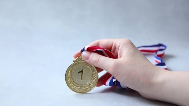 Hand holding winnaar of kampioen gouden trofee medaille op beton steen grijze achtergrond. Overwinning eerste plaats van de concurrentie. Winnings- of succesconcept. — Stockvideo