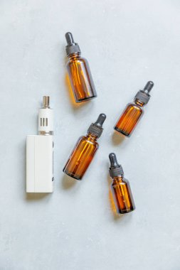 Buharlaştırma cihazı elektronik sigara ve beton gri arka planda sıvı şişeler. Alternatif sigara içmek için bir cihaz. Vaping dükkanı konsepti. Vaper için Gadget. Buhar aksesuarları