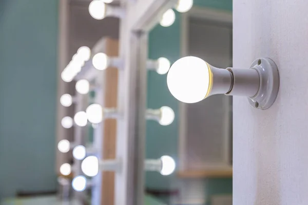 Empty woman makeup place with mirror and bulbs. Workplace makeup artist in modern makeup room. Barbershop interior. Dressing room with makeup mirror and table. Modern classical style interior design