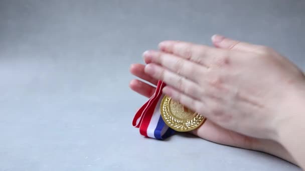 Hand holding winnaar of kampioen gouden trofee medaille op beton steen grijze achtergrond. Overwinning eerste plaats van de concurrentie. Winnings- of succesconcept. — Stockvideo