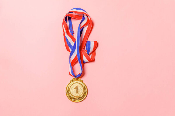 Simply flat lay design winner or champion gold trophy medal isolated on pink colorful background. Victory first place of competition. Winning or success concept. Top view copy space.
