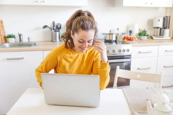 Mobiel kantoor thuis. Een jonge vrouw die thuis in de keuken werkt met een laptop. Lifestyle meisje studeren of werken binnen. Quarantaineconcept voor freelance bedrijven. — Stockfoto