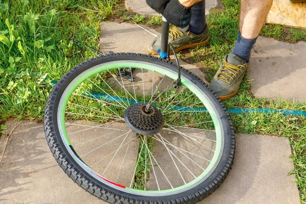 Bike mechanic man repairs bicycle in bicycle repair shop, outdoor. Hand of cyclist bicyclist examines, fixes modern cycle transmission system. Bike maintenance, sport shop concept