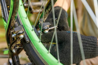 Bisikletli tamirci dışarıdaki bisiklet tamirhanesinde bisiklet tamir ediyor. Bisikletçinin eli modern bisiklet iletim sistemini inceliyor, tamir ediyor. Bisiklet bakımı, spor mağazası konsepti