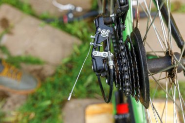 Bisikletli tamirci dışarıdaki bisiklet tamirhanesinde bisiklet tamir ediyor. Bisikletçinin eli modern bisiklet iletim sistemini inceliyor, tamir ediyor. Bisiklet bakımı, spor mağazası konsepti