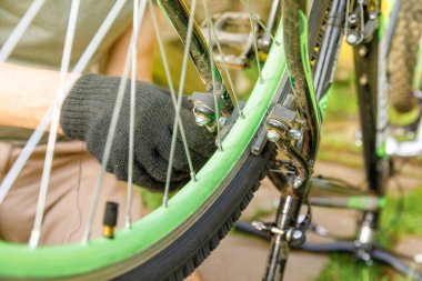 Bisikletli tamirci dışarıdaki bisiklet tamirhanesinde bisiklet tamir ediyor. Bisikletçinin eli modern bisiklet iletim sistemini inceliyor, tamir ediyor. Bisiklet bakımı, spor mağazası konsepti