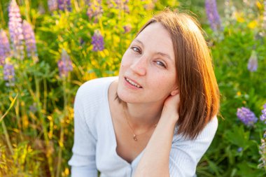 Dışarıda gülümseyen mutlu kız. Güzel, genç, esmer bir kadın çiçek açan yeşil arka planıyla yaz tarlasında dinleniyor. Özgür mutlu Avrupalı kadın. Olumlu insani duygu yüz ifadesi
