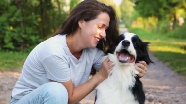Gülümseyen genç ve çekici bir kadın yaz sezonu arka planında sevimli köpek yavrusu çoban köpeğiyle oynuyor. Kucaklayan köpek arkadaşını kucaklayan bir kız. Hayvan bakımı ve hayvan bakımı kavramı.
