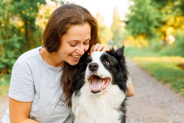 Lachende jonge aantrekkelijke vrouw spelen met schattige puppy hondengrens collie op zomer outdoor achtergrond. Meisje dat knuffelende hondenvriend omhelst. Dierenverzorging en dierenwelzijn. — Stockfoto