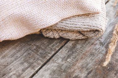 Sonbahar ya da kış geçmişi. Bir yığın yün kazak ve ahşap masada kurutulmuş bitki. Hygge havası, soğuk hava konsepti. El yapımı örgü kazaklar.