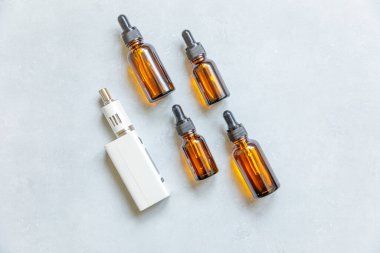 Buharlaştırma cihazı elektronik sigara ve beton gri arka planda sıvı şişeler. Alternatif sigara içmek için bir cihaz. Vaping dükkanı konsepti. Vaper için Gadget. Buhar aksesuarları.