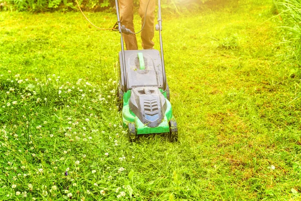 Hombre cortando hierba verde con cortacésped en el patio trasero. Jardinería país estilo de vida fondo. Hermosa vista sobre césped de hierba verde fresca a la luz del sol, paisaje de jardín en primavera o verano. — Foto de Stock