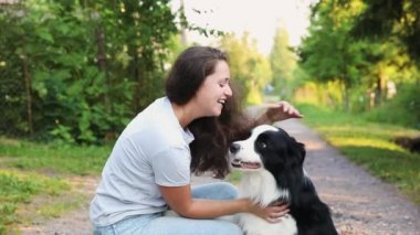 Gülümseyen genç ve çekici bir kadın yaz sezonu arka planında sevimli köpek yavrusu çoban köpeğiyle oynuyor. Kucaklayan köpek arkadaşını kucaklayan bir kız. Hayvan bakımı ve hayvan bakımı kavramı.