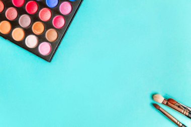 Makeup tools eyeshadow palette and brushes on blue background