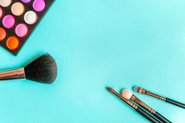Makeup tools eyeshadow palette and brushes on blue background