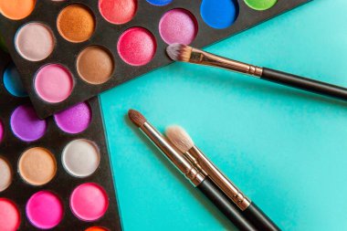 Makeup tools eyeshadow palette and brushes on blue background
