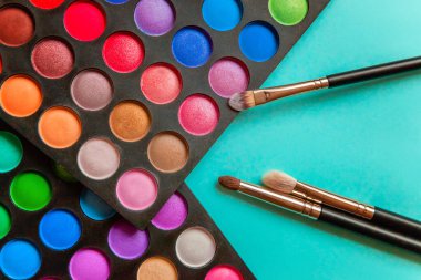 Makeup tools eyeshadow palette and brushes on blue background