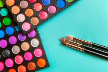Makeup tools eyeshadow palette and brushes on blue background