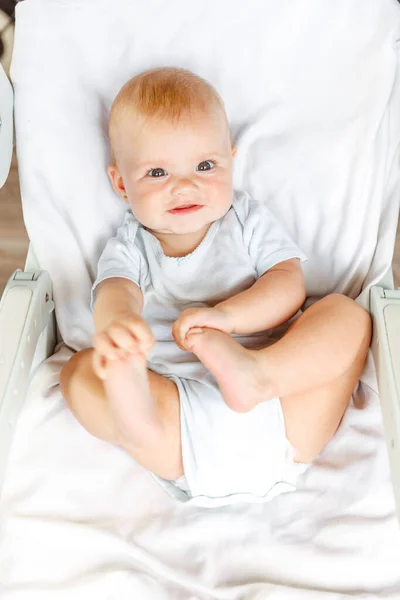 Χαριτωμένο μικρό νεογέννητο κορίτσι με χαμογελαστό πρόσωπο κοιτάζοντας κάμερα σε λευκό φόντο. Το μωρό αναπαύεται ξαπλωμένο στο κρεβάτι του κρεβατιού στο σπίτι. Μητρότητα ευτυχισμένη έννοια του παιδιού. — Φωτογραφία Αρχείου