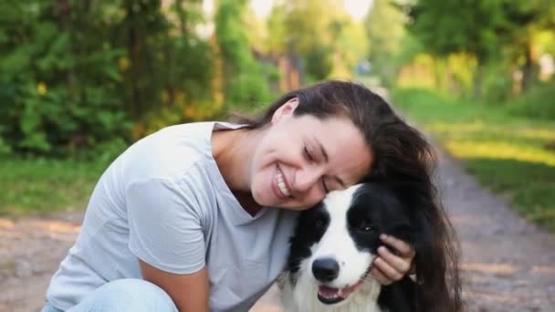 Sorridente giovane donna attraente che gioca con carino collie bordo cane cucciolo su sfondo esterno estate. Ragazza che abbraccia un amico cane abbracciato. Cura degli animali e concetto di animali. — Video Stock