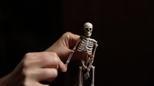 Dolcetto o scherzetto. Preparazione per la festa di Halloween. Donna mano tenendo spaventoso mostro scheletro decorazione tradizionale su sfondo nero scuro. Autunno autunno felice Halloween. — Video Stock