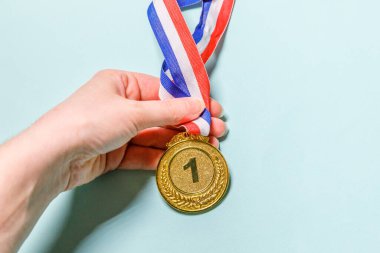 Mavi renkli arka planda izole edilmiş düz dizayn edilmiş el ele tutuşmada kazanan ya da şampiyon altın kupa madalyası. Yarışmanın birinciliği. Kazanmak ya da başarı konsepti. Üst görünüm kopyalama alanı