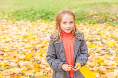 Sarı yapraklarla oynayan mutlu genç bir kız güzel bir sonbahar parkında doğa yürüyüşünde. Sonbahar portakal yaprağı tutan küçük çocuk.