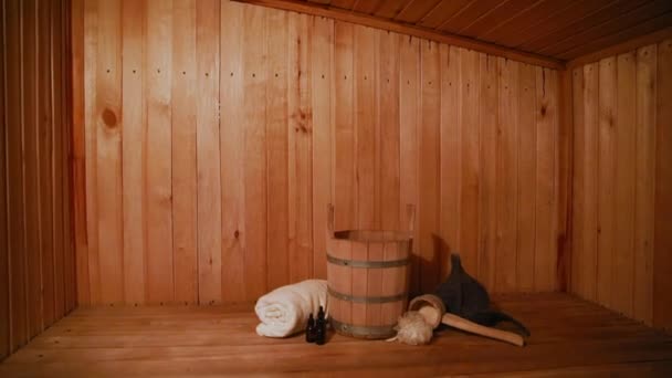 Tradiční stará ruská lázeňská koncepce lázní. Detail interiéru Finská sauna parní saunová místnost s tradičním saunovým příslušenstvím set povodí ručník aroma olej naběračka plsť. Relax country vesnice lázně koncept. — Stock video