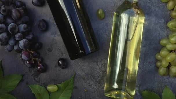 Vista dall'alto di bottiglia di vino rosso e bianco, vite verde, bicchiere da vino e uva matura su sfondo tavolo in pietra scura vintage. Wine shop enoteca cantina o concetto di degustazione di vini. — Video Stock