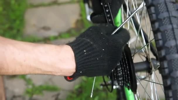 Mecánico de bicicletas reparaciones hombre bicicleta en taller de reparación de bicicletas, al aire libre. Mano de ciclista ciclista examina, fija el sistema de transmisión de ciclo moderno. Mantenimiento de bicicletas, concepto de tienda de deporte. — Vídeo de stock