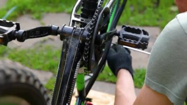 Bisikletli tamirci dışarıdaki bisiklet tamirhanesinde bisiklet tamir ediyor. Bisikletçinin eli modern bisiklet iletim sistemini inceliyor, tamir ediyor. Bisiklet bakımı, spor mağazası konsepti.